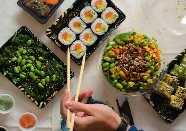 Persona comiendo comida japonesa con palillos 