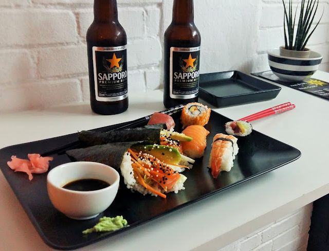 Plato de comida japonesa en mesa con cervezas